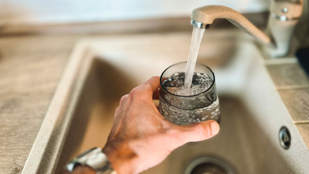 man filling water glass from faucet