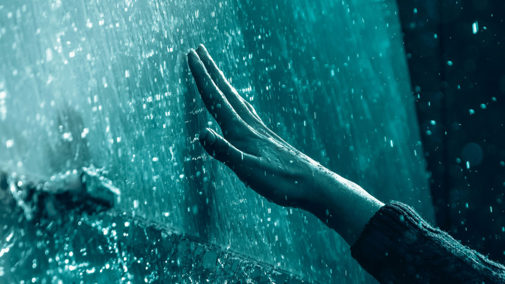 person touching the blue wall of water
